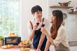 © Crystal - Happy couple toasting red wine, smiling and celebrating. Preparing food, cooking together at home kitchen