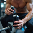 © miss irine - Man with muscular body holds two black cans in gym. Person drinks beverage near barbell. Athlete rests after workout session, recovers strength, energy.