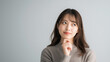 © mei - 考える仕草をする日本人女性のポートレート コピースペースあり 判断や検討のイメージ