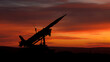 © photo for everything - Silhouette of a missile launcher at dramatic sunset, with vibrant orange and red skies, suggesting themes of power, defense, and conflict