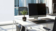 © zyla - Photograph of a minimalist modern office desk with a blank computer screen and small plant.