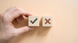 © Gambar - Hand selecting a wooden cube with a checkmark, next to a cube with a cross