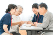 © buritora - Female patients and male and female caregivers performing bean-grabbing exercises at nursing homes, hospitals, and rehabilitation centers.