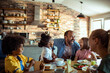 © Davor - Happy family laughing together at breakfast in home kitchen