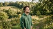© AAA - Young man enjoying peaceful nature walk in sunny countryside meadow, eyes closed breathing fresh air, surrounded by green hills, trees and warm golden light
