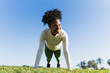 © Westend61 - Athlete doing push up outdoors on grass in sunny morning