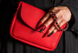 © VISTA by Westend61 - Hand with red manicure holding red textured bag and gummy bear jewelry
