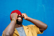 © VISTA by Westend61 - Smiling man with beanie laughing against blue wall in urban setting