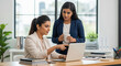 © PRASANNAPIX - Two Professional Indian Businesswomen Collaborating on Laptop in Modern Office