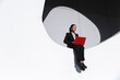 © VISTA by Westend61 - Businesswoman working with red laptop on white circle in Barcelona