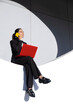 © VISTA by Westend61 - Businesswoman multitasking with smartphone and red laptop outdoors