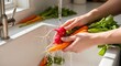 © miati - Woman washing vegetables in kitchen sink.