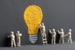 © Worrapol - Illuminating Ideas: Miniature figures collaborate to bring a vibrant lightbulb idea to life, symbolizing the collective effort behind innovation and creative thinking.