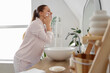 © Pixel-Shot - Young woman with soap washing her face near mirror in bathroom