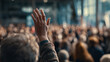 © Shelley - Person Raising Hand in Blurred Audience at Business Conference, Seeking Attention in Engaging Town Hall Meeting