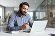 © insta_photos - Young bearded indian business man teacher talking, teleworking, having virtual classroom meeting working on laptop computer giving online webinar training, remote class on video conference call.