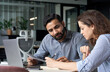 © insta_photos - Two multiethnic professionals colleagues working together with laptop and papers in office. Indian male mentor and latin female young professional sitting in creative office space.