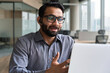 © insta_photos - Indian business man speaking having virtual meeting on laptop. Professional remote online customer service support manager wearing headset talking consulting on video call at home office call center.