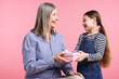 © New Africa - Little girl greeting her grandmother with gift on pink background