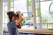 © ADDICTIVE STOCK - Young woman with curly hair works from home taking photos near windows