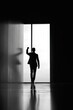 © Popelniushka - Backlit silhouette of a suited businessperson with a raised fist in a modern office setting
