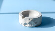 © Doni - Minimalist Concrete Ashtray on Soft Blue Background