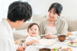 © buritora - Mothers and fathers feeding their babies solid food and meals at the dinner table (childcare/parenting)