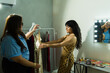 © AntonioDiaz - Stylist helping fashion model prepare outfit for photoshoot, backstage dressing room during fashion event