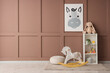 © Pixel-Shot - Shelf unit with toys and picture on brown wall in children's room