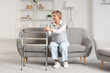 © Pixel-Shot - Mature woman with walker sitting on sofa at home