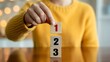 © Faheem - Person carefully placing a wooden block with number one on a stack of two and three blocks symbolizing priorit
