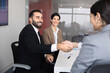 © fizkes - Smiling male executive and female partners exchanging professional handshake, as business partnership agreement, closing commercial deal, finalizing successfully corporate meeting. Collaboration