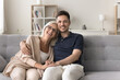 © fizkes - Happy woman enjoy time with young adult son. Multigenerational people, family sitting on sofa, posing for camera, looking happy and satisfied spend carefree, pleasant weekend leisure together at home