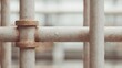 © CYBERPINK - Close-up of a rusted metal pipe or railing. the pipe appears to be old and weathered, with visible signs of wear and tear. the metal is a light beige color and has a rough texture.