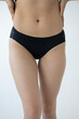 © Victoria - woman in black panties, lingerie theme. Close-up view of sexy slim caucasian woman standing against grey background. Woman wears black lace panties. Fashion and sensuality theme.