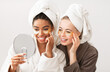 © Prostock-studio - Home spa. Pleasant young multiracial young women putting eye patches and looking at mirror
