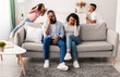 © Prostock-studio - Bad Behavior Concept, Siblings Conflict. African American sister and brother having quarrel, pulling out tongue and fooling over their tired parents. Desperate mother and dad feeling headache