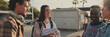 © Andrii Nekrasov - Group of students are chatting while standing outside. Cheerful students are talking and laughing standing outside with books. Panoramic