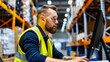 © savittree - Focused Male Warehouse Worker Wearing Safety Vest Working on Computer in Distribution Center Environment