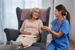 © Surachai - Healthcare interaction nurse engaging with elderly patient in home environment compassionate care warm atmosphere