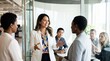 © ryker - Diverse businesswoman leading small team meeting in modern glass office, smiling and gesturing while colleagues listen attentively and take notes
