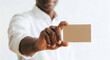© Rashed - Man in white shirt holding out a blank brown card for business or identification purposes