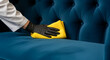 © Inspire Shots Hub - Hand in black glove cleans blue velvet sofa with yellow microfiber cloth, representing care, hygiene, and domestic service, ideal for cleaning concept