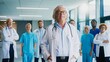 © VAKSMANV - Adult male doctor holding relaxed posture while standing before medical team. Experienced medical professional showing calm authority while preparing for demanding hospital work. Working in hospital.