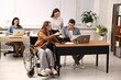 © New Africa - Inclusion. Woman in wheelchair and her colleagues working in office