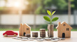 © VectorGenius - A red toy car is parked next to wooden houses and coins with a plant growing in a stack of coins on a table.