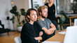 © dinatychynska - Dissatisfied woman with crossed arms sits beside unhappy male colleague at office table, while third coworker stands behind, showing team conflict and workplace tension.