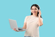 © Pixel-Shot - Female programmer in headphones with laptop on blue background