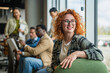 © Miljan Živković - Smiling redhead woman student working in modern office startup