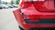 © Olga Ко - Para-choque traseiro amassado e arranhado de um carro vermelho. Conceito de acidente de trânsito e seguro automotivo.